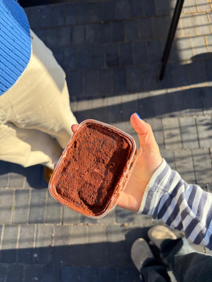 Tiramisù portion held outdoors at an event